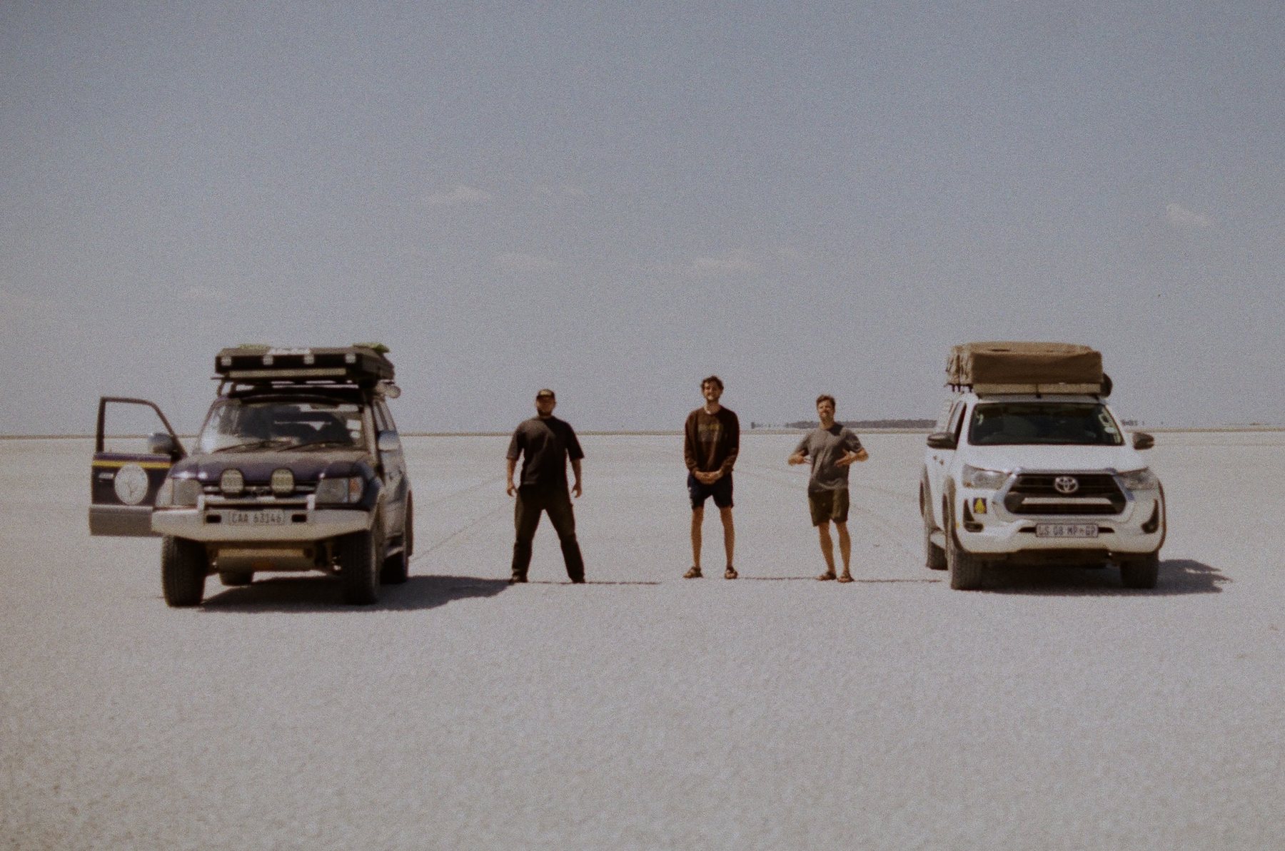 Two 4x4s and three travellers on the vast white expanse of the Makgadikgadi salt pans