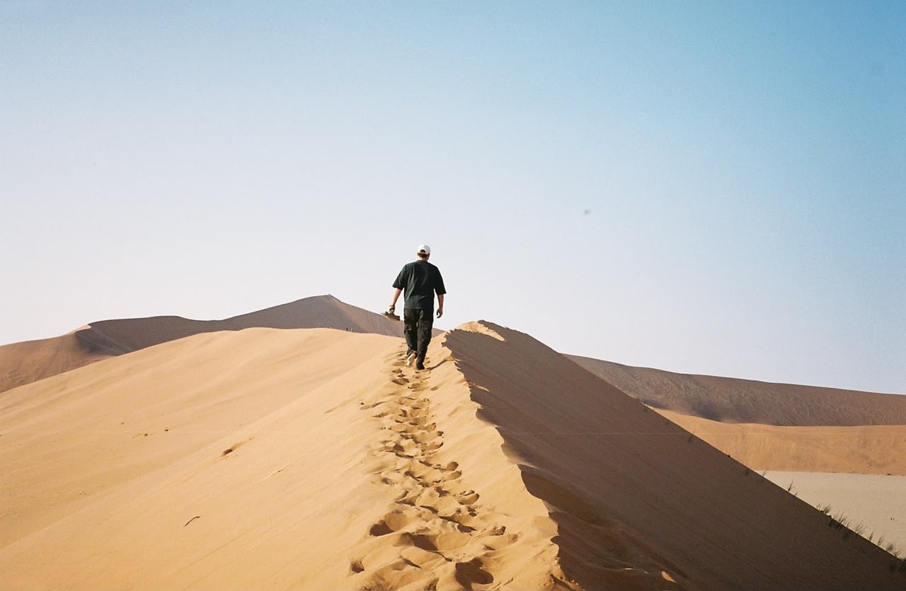 A lone figure walking the ridge of a towering red dune at Sossusvlei